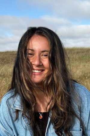 Headshot of Magaly smiling with dry grass in background